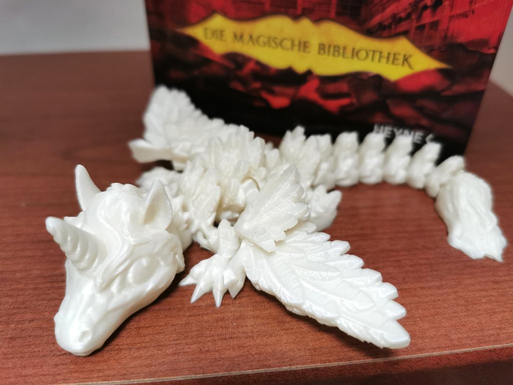 Drachin LUMIRA majestätische weiße Einhorn-Drachin mit Flügeln vor einem Buch